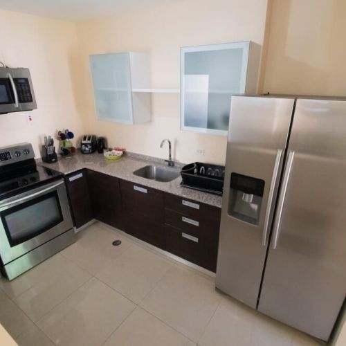 Another angle of the modern kitchen highlighting the stainless double-door fridge, undermount sink, ample granite counter space and contemporary cabinetry.