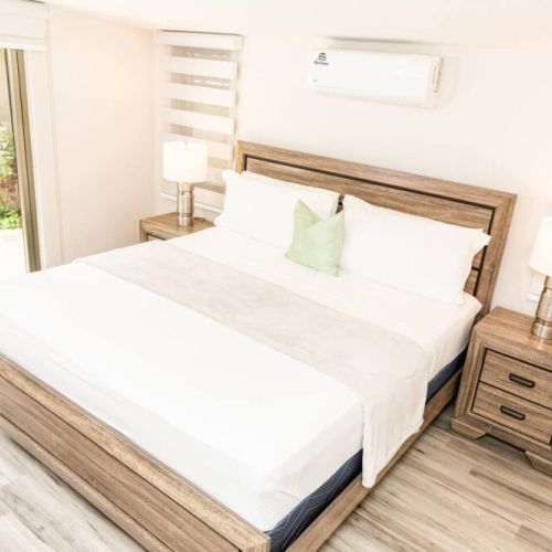 Serene bedroom with queen bed, wooden headboard, bedside tables and green accent pillow