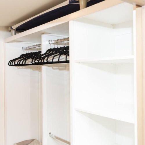 Spacious closet with hanging rod, hangers, and open shelving for organized storage
