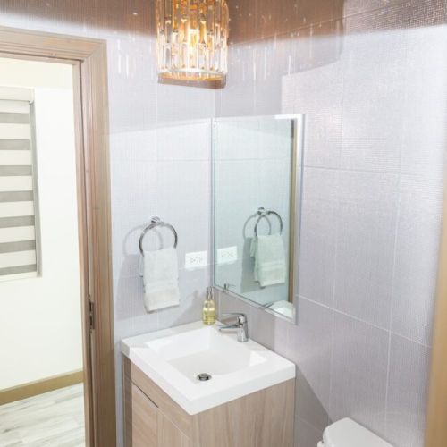 Stylish powder room with modern vanity sink, wall-mounted mirror, towel ring and decorative light fixture