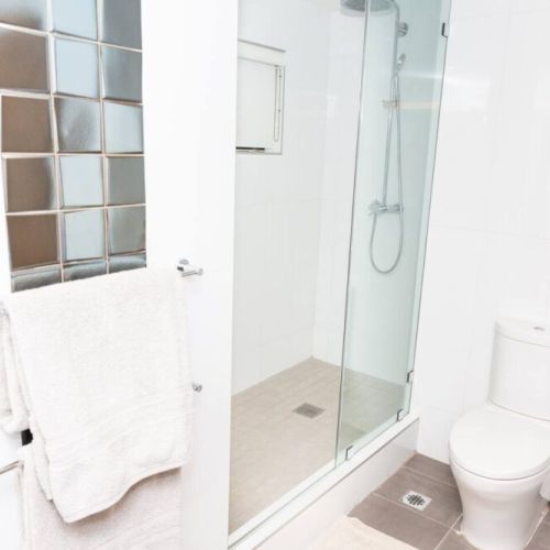 Bright bathroom with glass-enclosed shower, glass block accent wall and modern toilet