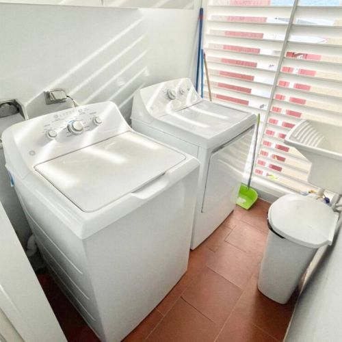 Laundry area with washer and dryer, utility sink and cleaning supplies adjacent to window