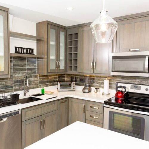 Modern kitchen with stainless steel appliances, glass-front cabinets and mosaic tile backsplash